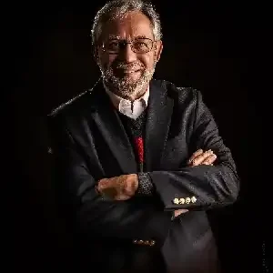 Rev. William Webster, transitional pastor, posed with arms crossed, wearing a suit jacket over a sweater and collared shirt.